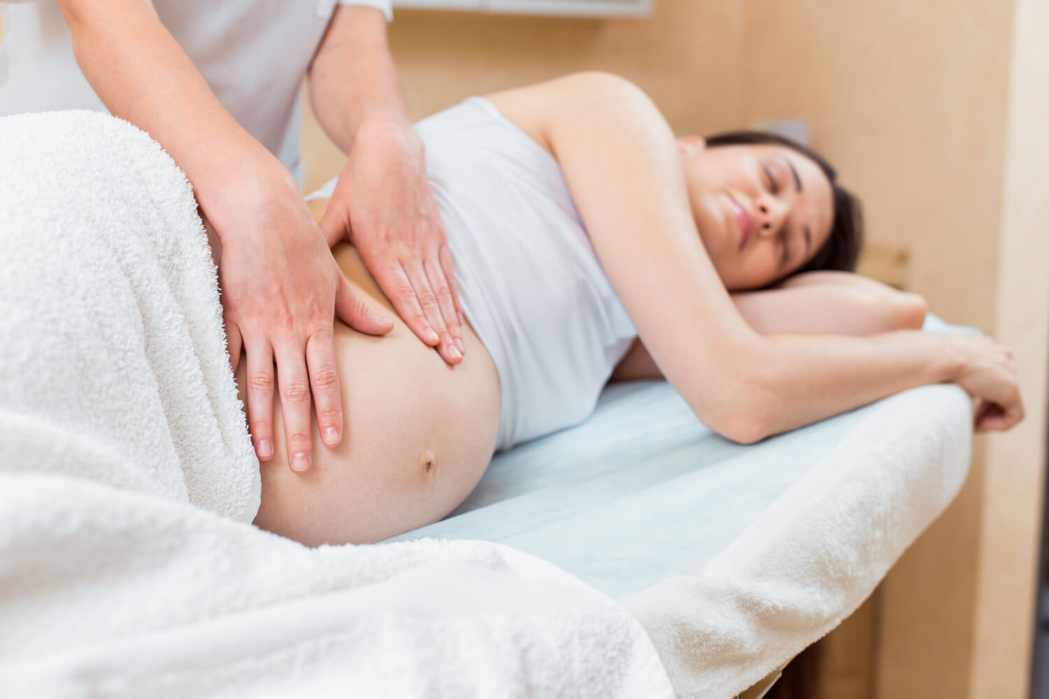 beautiful-pregnant-brunette-with-long-hair-lies-her-side-reception-with-massage-therapist-cosmetology-room (1)